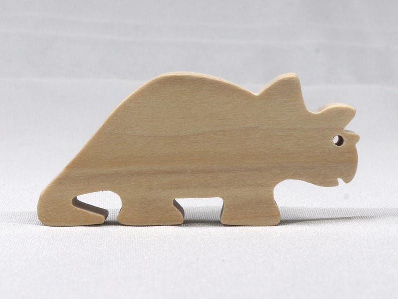 This is an unfinished wooden Wooden Toy Dinosaur Triceratops cutout from solid wood using traditional woodworking techniques. Sanded smooth and ready to paint, stain, or customize. Freestanding design for small hands, toddlers, young children, crafters, collectors, and display. I take custom orders for any animal, quantity, and mix — including large ornament orders. Mix and match, request a different size, or send a drawing or pattern. Handmade by Odin's Toy Factory in Tallahassee, Florida, USA.