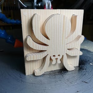 Handmade unfinished wooden Halloween spider cutout from Odin's Toy Factory Snazzy Spooks Collection. Solid wood hand-cut spider, paintable, freestanding design. Approximate size 3.5 inches height by 3.5 inches width by 0.75 inches thick. Made in Tallahassee, Florida, USA.