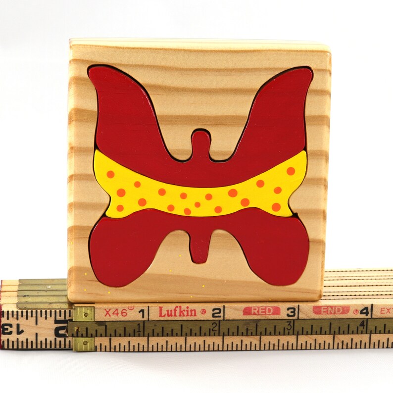 A wooden three-piece butterfly tray puzzle, handmade and finished. The butterfly is painted bright red and yellow with orange spots. The wooden tray is finished with clear shellac. It is one of four puzzles in my Puzzle Pals Collection.