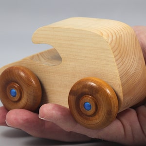 Handmade wooden toy car. The body is finished with clear shellac, and the wheels are finished with amber shellac. The hubs are painted with metallic sapphire blue trim.