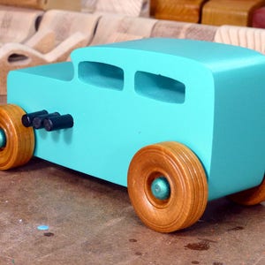 Handmade wooden toy car, 1932 Hot Rod Sedan, painted turquoise with metallic green and black trim. The wheels are finished with nonmarring amber shellac. Handcrafted from natural wood in Tallahassee, Florida, USA. Approximate size: 6 inches long, 3 inches high, 2.5 inches wide. Odin's Toy Factory custom wooden toy.