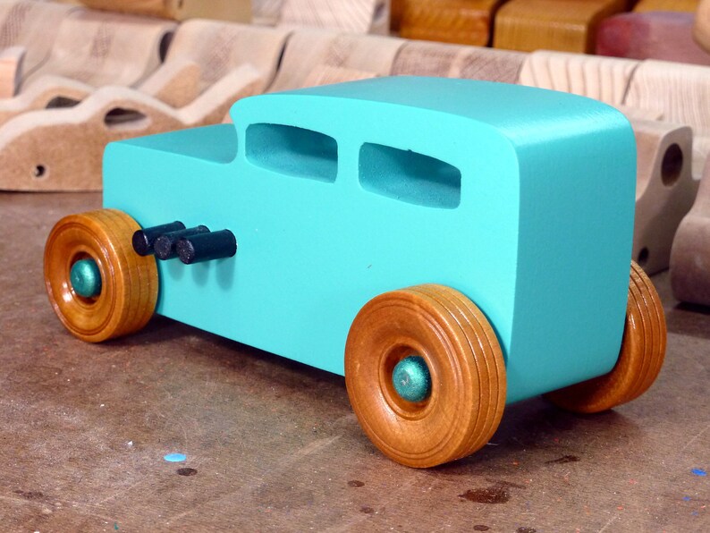 Handmade wooden toy car, 1932 Hot Rod Sedan, painted turquoise with metallic green and black trim. The wheels are finished with nonmarring amber shellac. Handcrafted from natural wood in Tallahassee, Florida, USA. Approximate size: 6 inches long, 3 inches high, 2.5 inches wide. Odin's Toy Factory custom wooden toy.
