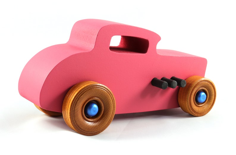 This is a handmade wooden Hot Rod '32 Deuce Coupe toy car. It is hand-painted hot pink with black and metallic sapphire blue trim. The hardwood wheels are finished with nonmarring amber shellac.