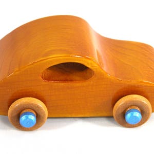 A handmade wooden toy car modeled after the iconic 1957 bug, finished with amber shellac and metallic sapphire blue trim. It's part of my Play Pal Collection.