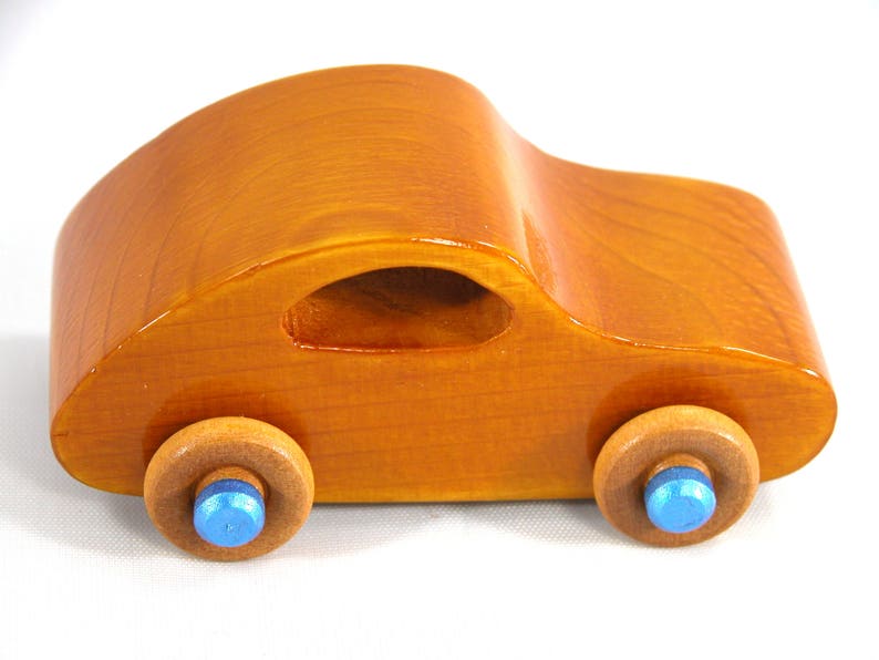 A handmade wooden toy car modeled after the iconic 1957 bug, finished with amber shellac and metallic sapphire blue trim. It's part of my Play Pal Collection.