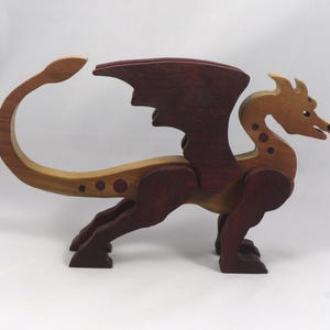 Handmade wooden dragon figurine made from contrasting hardwoods with a light natural wood body and head paired with rich dark reddish-brown wings, legs, and horns.