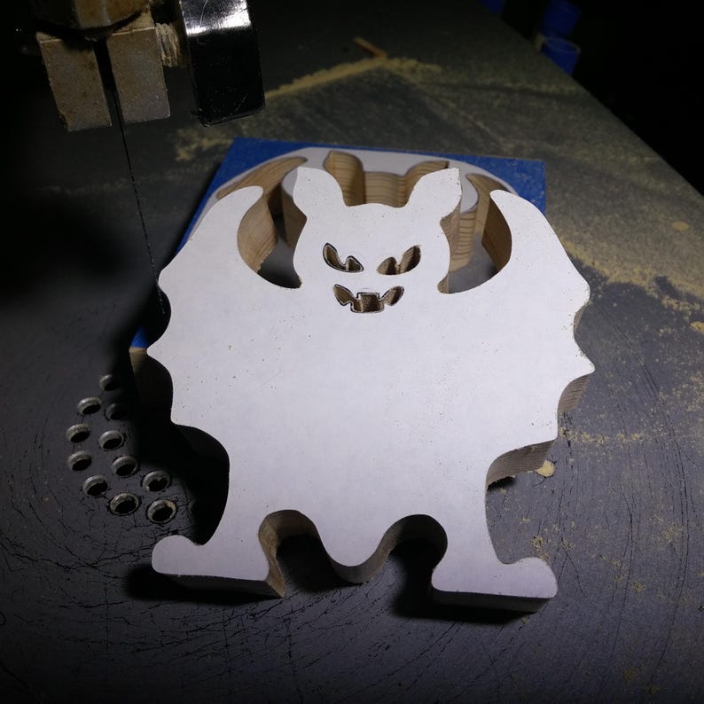 Handmade unpainted wooden Halloween bat cutout, freestanding light-colored solid wood figure with spooky carved face and outstretched wings, ready to paint, from my Snazzy Spooks collection from Odin's Toy Factory in Tallahassee Florida.