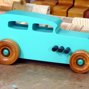 Handmade wooden toy car, 1932 Hot Rod Sedan, painted turquoise with metallic green and black trim. The wheels are finished with nonmarring amber shellac. Handcrafted from natural wood in Tallahassee, Florida, USA. Approximate size: 6 inches long, 3 inches high, 2.5 inches wide. Odin's Toy Factory custom wooden toy.