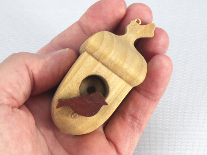 Handmade wooden miniature birdhouse ornament cut from wood with rounded edges, natural wood grain and color variations, finished with non-toxic shellac or food-safe oils and beeswax, lightweight and ready to hang. Made in Tallahassee, Florida, USA, by Odin's Toy Factory.