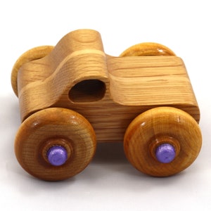 May include: A wooden toy car with a natural wood finish. The car has four large, round wheels with purple center caps. The body of the car is curved and features a cutout. A classic toy for children.