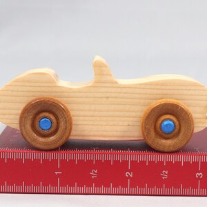 Handmade wooden toy car convertible sports coupe with a nontoxic satin polyethylene finish, amber shellac wheels, and metallic sapphire blue trim.
