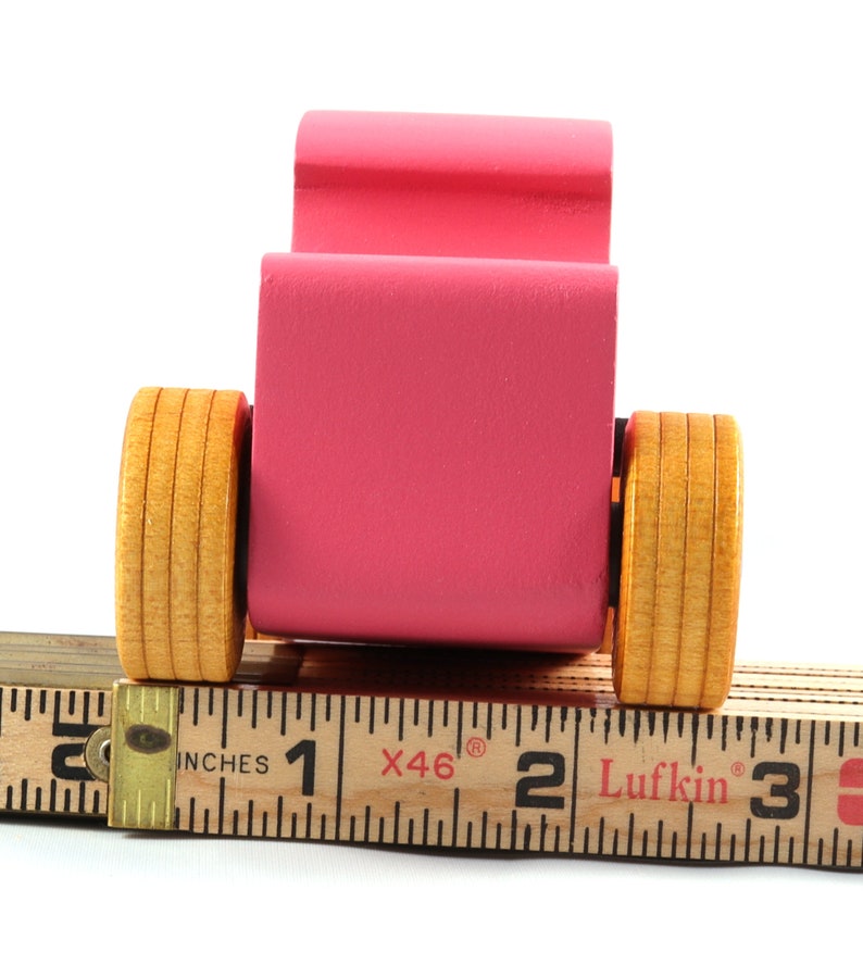 This is a handmade wooden Hot Rod '32 Deuce Coupe toy car. It is hand-painted hot pink with black and metallic sapphire blue trim. The hardwood wheels are finished with nonmarring amber shellac.