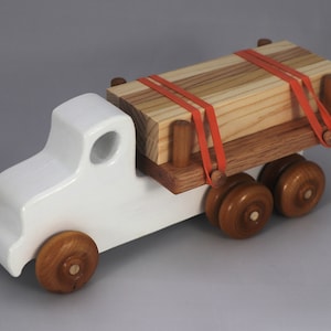 Handmade wooden toy lumber truck from Odin's Toy Factory Easy 5 Truck Fleet Collection. Painted lumber truck with acrylic body, shellac bed, and wheels. Measures approximately 9 inches long, 4 inches high, and 3.5 inches wide. Handmade in Tallahassee, Florida, USA. Custom colors available.