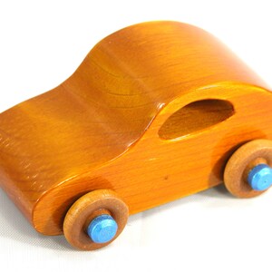 A handmade wooden toy car modeled after the iconic 1957 bug, finished with amber shellac and metallic sapphire blue trim. It's part of my Play Pal Collection.