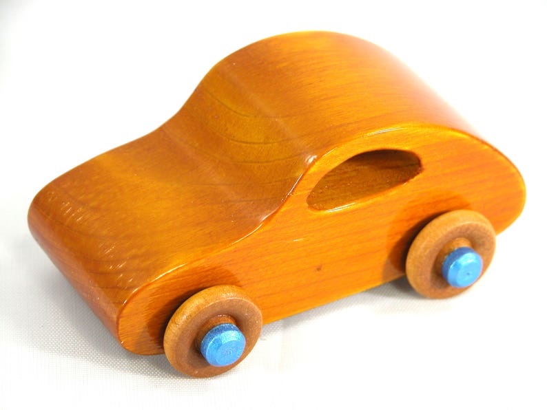 A handmade wooden toy car modeled after the iconic 1957 bug, finished with amber shellac and metallic sapphire blue trim. It's part of my Play Pal Collection.