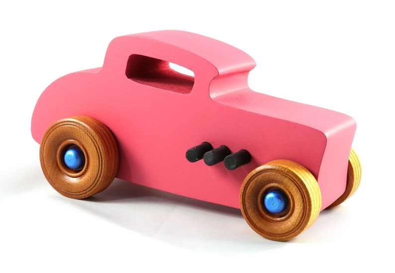 This is a handmade wooden Hot Rod '32 Deuce Coupe toy car. It is hand-painted hot pink with black and metallic sapphire blue trim. The hardwood wheels are finished with nonmarring amber shellac.