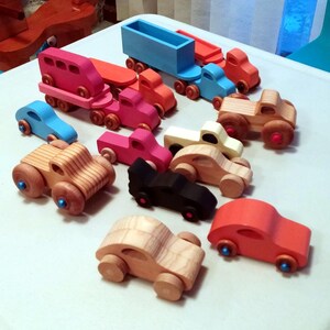 Play Pal Collection of handmade wooden toy cars, pickup trucks, vans, monster trucks, and trailer trucks in assorted colors and natural wood finishes.