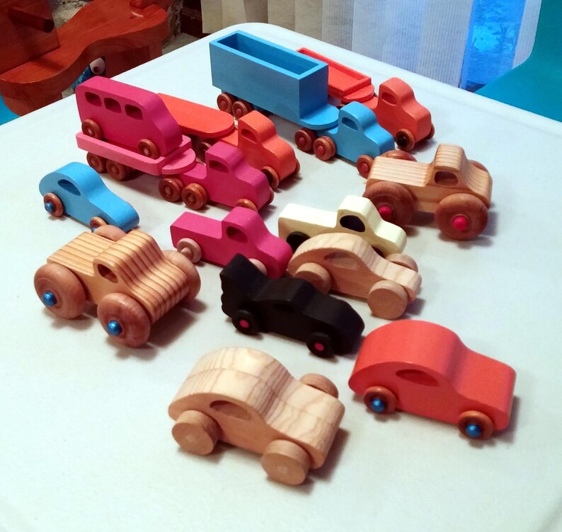 Play Pal Collection of handmade wooden toy cars, pickup trucks, vans, monster trucks, and trailer trucks in assorted colors and natural wood finishes.
