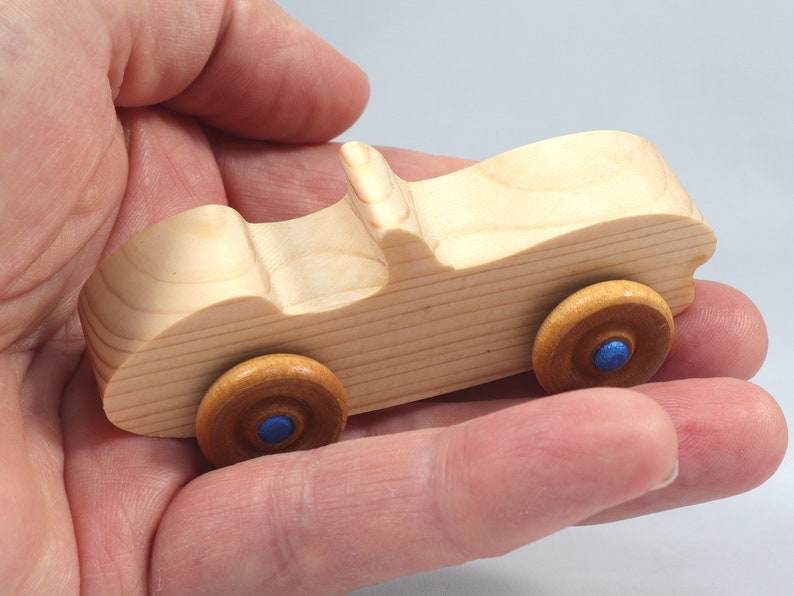 Handmade wooden toy car convertible sports coupe with a nontoxic satin polyethylene finish, amber shellac wheels, and metallic sapphire blue trim.