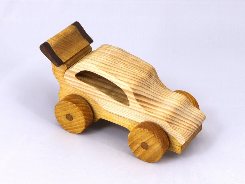 Handmade wooden toy car finished with nontoxic clear amber shellac and contrasting wood trim. Part of the Speedy Wheels Collection. Handcrafted in Tallahassee, Florida, USA. Length 5-1/2 inches, width 2-1/2 inches, height 2-1/2 inches. Made at Odin's Toy Factory.
