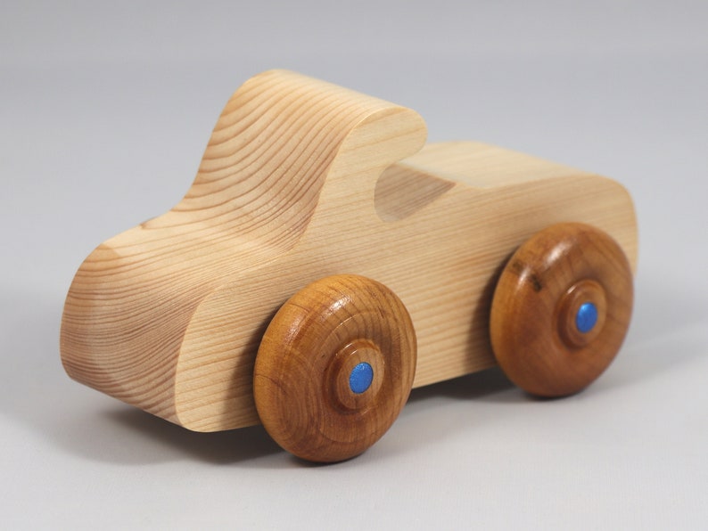 Handmade wooden toy car. The body is finished with clear shellac, and the wheels are finished with amber shellac. The hubs are painted with metallic sapphire blue trim.