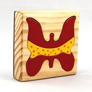 A wooden three-piece butterfly tray puzzle, handmade and finished. The butterfly is painted bright red and yellow with orange spots. The wooden tray is finished with clear shellac. It is one of four puzzles in my Puzzle Pals Collection.