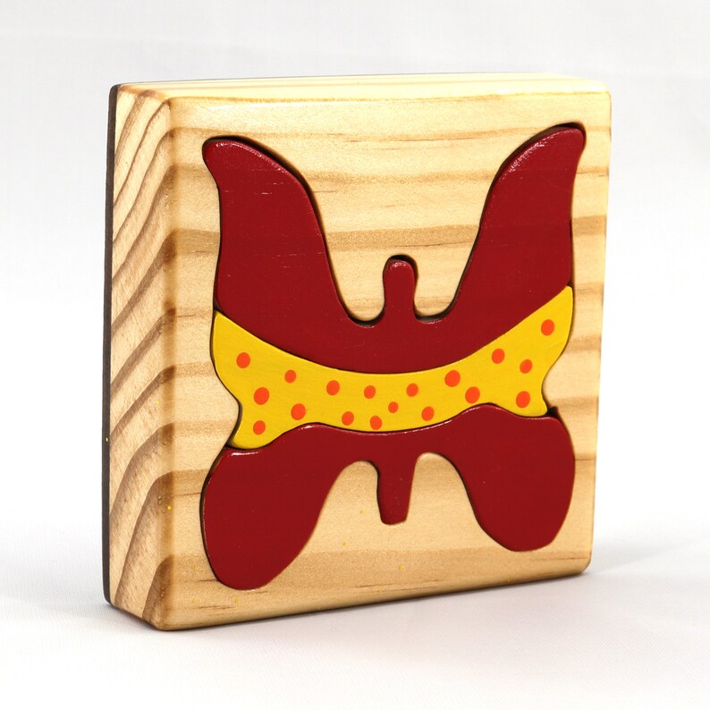 A wooden three-piece butterfly tray puzzle, handmade and finished. The butterfly is painted bright red and yellow with orange spots. The wooden tray is finished with clear shellac. It is one of four puzzles in my Puzzle Pals Collection.