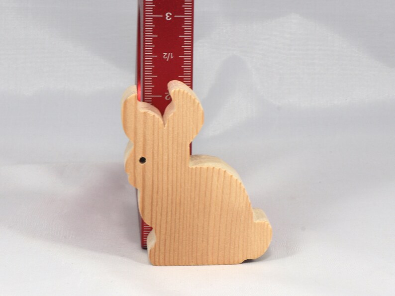 May include: A wooden rabbit figurine, approximately 3 inches tall, with a light brown color and a smooth, natural finish.