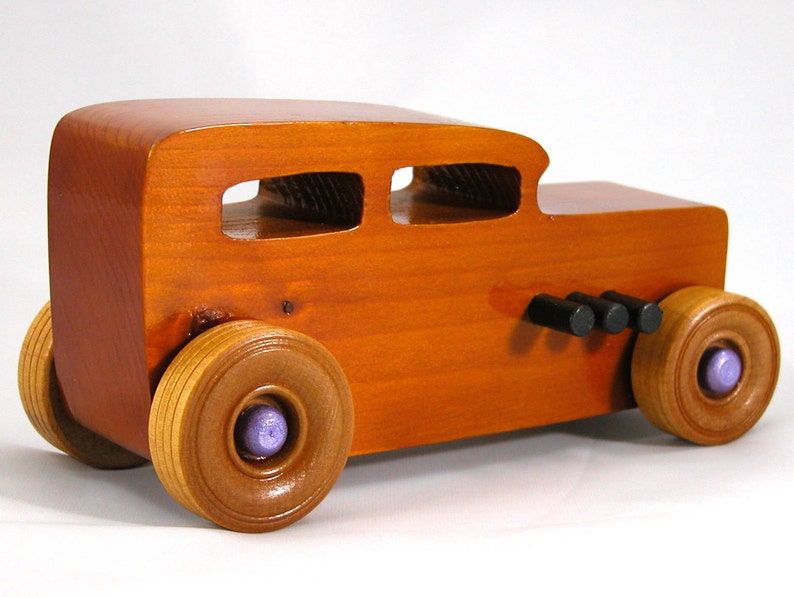 This is a handmade wooden toy car modeled after a Hot Rod 1932 Ford Sedan. It is made from wood, finished with multiple coats of amber shellac, and trimmed with black and metallic purple acrylic paint.