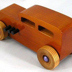 This is a handmade wooden toy car modeled after a Hot Rod 1932 Ford Sedan. It is made from wood, finished with multiple coats of amber shellac, and trimmed with black and metallic purple acrylic paint.