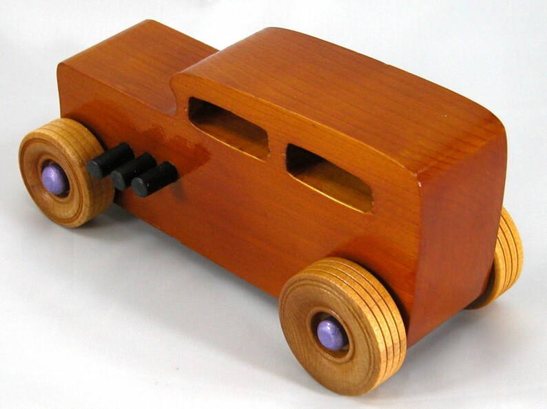This is a handmade wooden toy car modeled after a Hot Rod 1932 Ford Sedan. It is made from wood, finished with multiple coats of amber shellac, and trimmed with black and metallic purple acrylic paint.