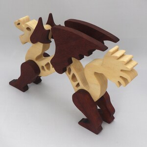 Handmade wooden dragon figurine. crafted from contrasting hardwoods with a light natural wood body and head paired with rich dark reddish-brown wings, legs, and horns.