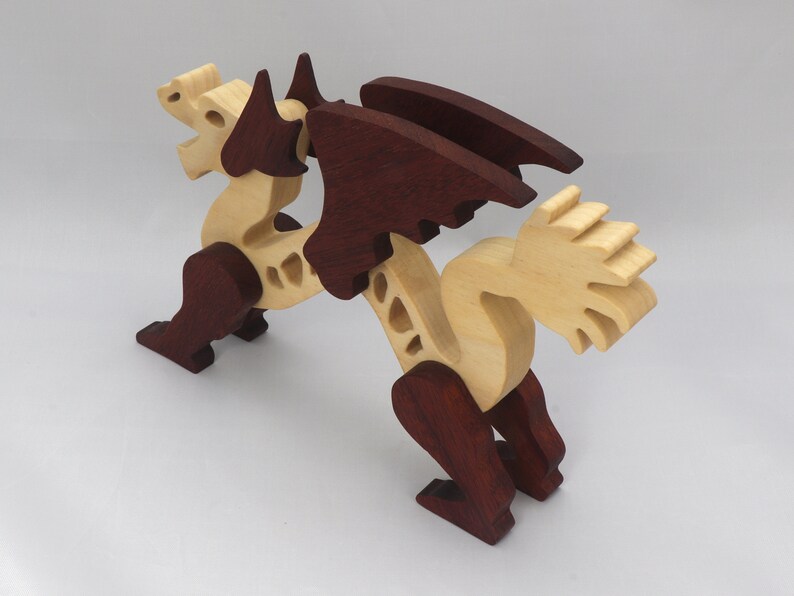 Handmade wooden dragon figurine. crafted from contrasting hardwoods with a light natural wood body and head paired with rich dark reddish-brown wings, legs, and horns.
