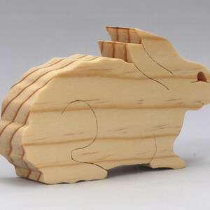 This is an unfinished wooden Rabbit cutout from solid wood using traditional woodworking techniques. Sanded smooth and ready to paint, stain, or customize. Freestanding design for small hands, toddlers, young children, crafters, collectors, and display. I take custom orders for any animal, quantity, and mix — including large ornament orders. Mix and match, request a different size, or send a drawing or pattern. Handmade by Odin's Toy Factory in Tallahassee, Florida, USA.