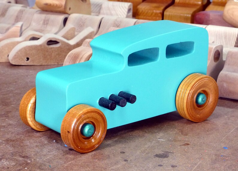Handmade wooden toy car, 1932 Hot Rod Sedan, painted turquoise with metallic green and black trim. The wheels are finished with nonmarring amber shellac. Handcrafted from natural wood in Tallahassee, Florida, USA. Approximate size: 6 inches long, 3 inches high, 2.5 inches wide. Odin's Toy Factory custom wooden toy.