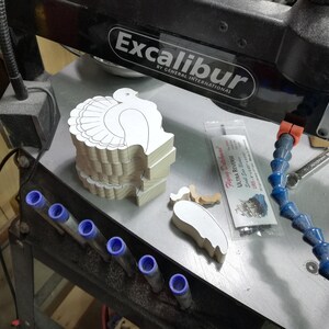 Stacked unfinished wooden turkey shapes and separate wing pieces on my Excabur Ex-21 scroll saw in the workshop.