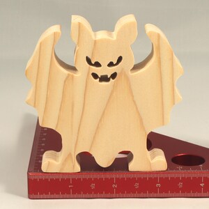Handmade unpainted wooden Halloween bat cutout, freestanding light-colored solid wood figure with spooky carved face and outstretched wings, ready to paint, from my Snazzy Spooks collection. Standing on a ruler.