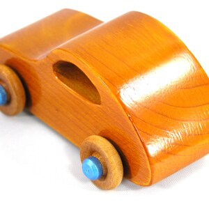 A handmade wooden toy car modeled after the iconic 1957 bug, finished with amber shellac and metallic sapphire blue trim. It's part of my Play Pal Collection.