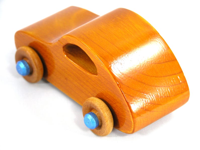 A handmade wooden toy car modeled after the iconic 1957 bug, finished with amber shellac and metallic sapphire blue trim. It's part of my Play Pal Collection.