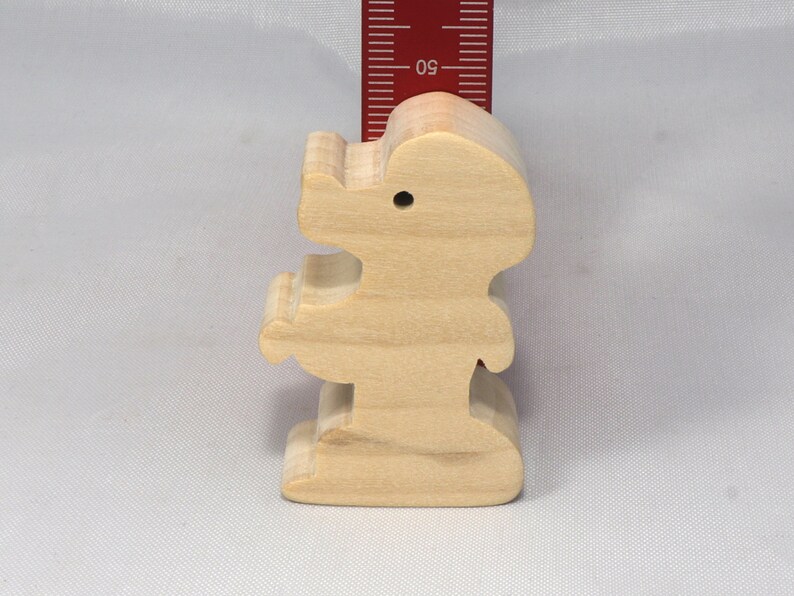 May include: A wooden figurine of a person standing with arms outstretched. The figurine is made of light brown wood and is about 4 inches tall.