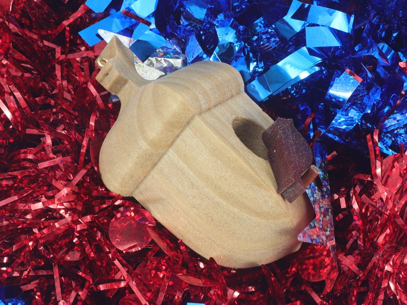 Handmade wooden miniature birdhouse ornament cut from wood with rounded edges, natural wood grain and color variations, finished with non-toxic shellac or food-safe oils and beeswax, lightweight and ready to hang. Made in Tallahassee, Florida, USA, by Odin's Toy Factory.