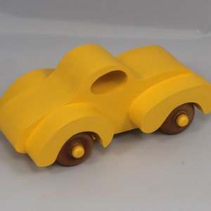 Handmade wooden toy car vintage style of a fat fendered coupe painted bright yellow with nonmarring amber shellac finished wheels. It is an excellent push toy for a younger child.