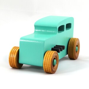 Handmade wooden toy car, 1932 Hot Rod Sedan, painted turquoise with metallic green and black trim. The wheels are finished with nonmarring amber shellac. Handcrafted from natural wood in Tallahassee, Florida, USA. Approximate size: 6 inches long, 3 inches high, 2.5 inches wide. Odin's Toy Factory custom wooden toy.