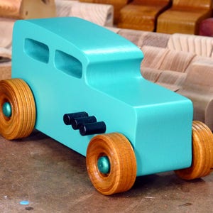 Handmade wooden toy car, 1932 Hot Rod Sedan, painted turquoise with metallic green and black trim. The wheels are finished with nonmarring amber shellac. Handcrafted from natural wood in Tallahassee, Florida, USA. Approximate size: 6 inches long, 3 inches high, 2.5 inches wide. Odin's Toy Factory custom wooden toy.