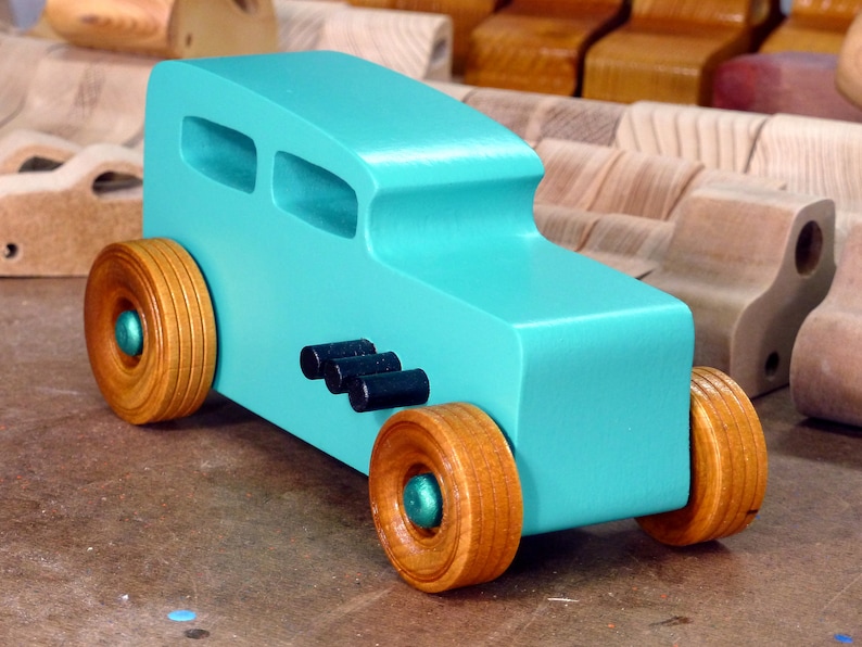 Handmade wooden toy car, 1932 Hot Rod Sedan, painted turquoise with metallic green and black trim. The wheels are finished with nonmarring amber shellac. Handcrafted from natural wood in Tallahassee, Florida, USA. Approximate size: 6 inches long, 3 inches high, 2.5 inches wide. Odin's Toy Factory custom wooden toy.