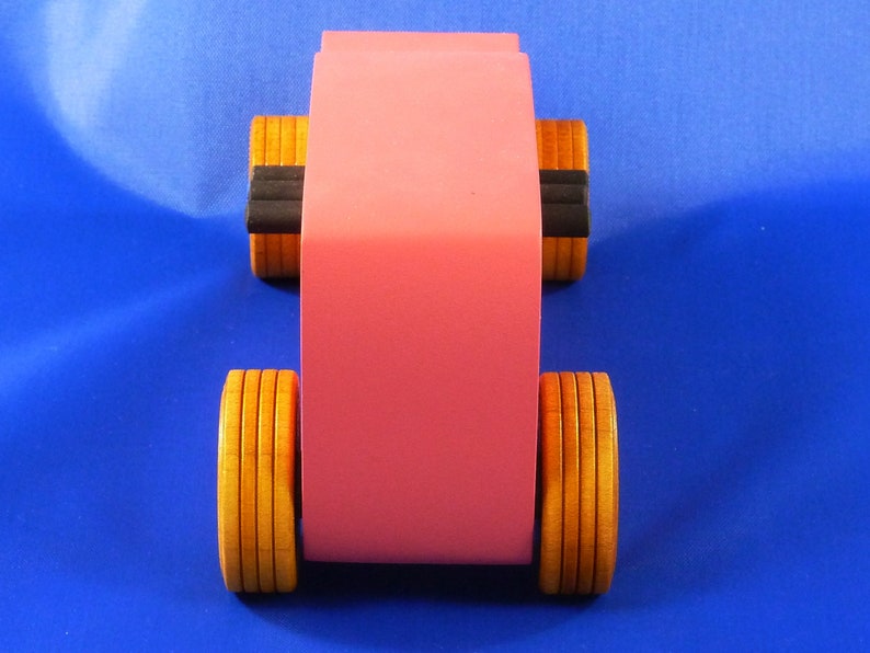 Handcrafted pink wooden hot rod '32 sedan toy car. Features black and metallic sapphire blue accents, and non-marking amber shellac wheels. Made to order for unique play or display.