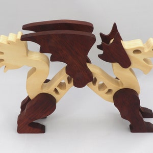 Handmade wooden dragon figurine. crafted from contrasting hardwoods with a light natural wood body and head paired with rich dark reddish-brown wings, legs, and horns.