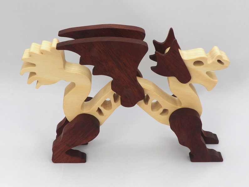 Handmade wooden dragon figurine. crafted from contrasting hardwoods with a light natural wood body and head paired with rich dark reddish-brown wings, legs, and horns.