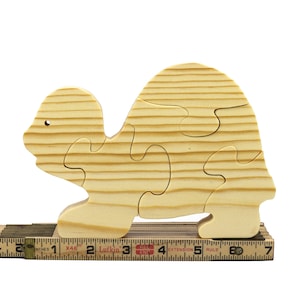 Handmade wooden turtle puzzle with 5 simple interlocking pieces. Freestanding 5-piece wooden puzzle. Approximate dimensions: 5 inches high by 7.25 inches long by 0.75 inches thick. Finished with mineral oil and beeswax blend. Handcrafted in Tallahassee, Florida, USA, using natural wood. Unique wood grain color and knot variations. Odin’s Toy Factory.