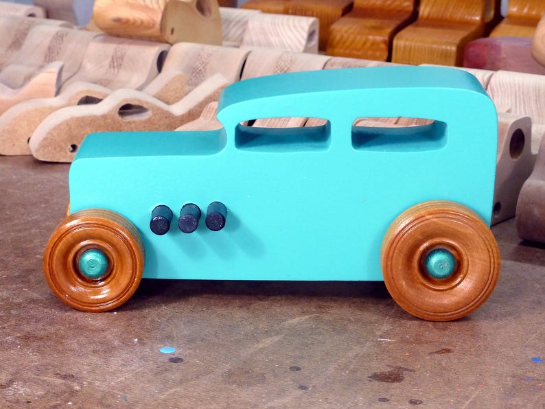 Handmade wooden toy car, 1932 Hot Rod Sedan, painted turquoise with metallic green and black trim. The wheels are finished with nonmarring amber shellac. Handcrafted from natural wood in Tallahassee, Florida, USA. Approximate size: 6 inches long, 3 inches high, 2.5 inches wide. Odin's Toy Factory custom wooden toy.